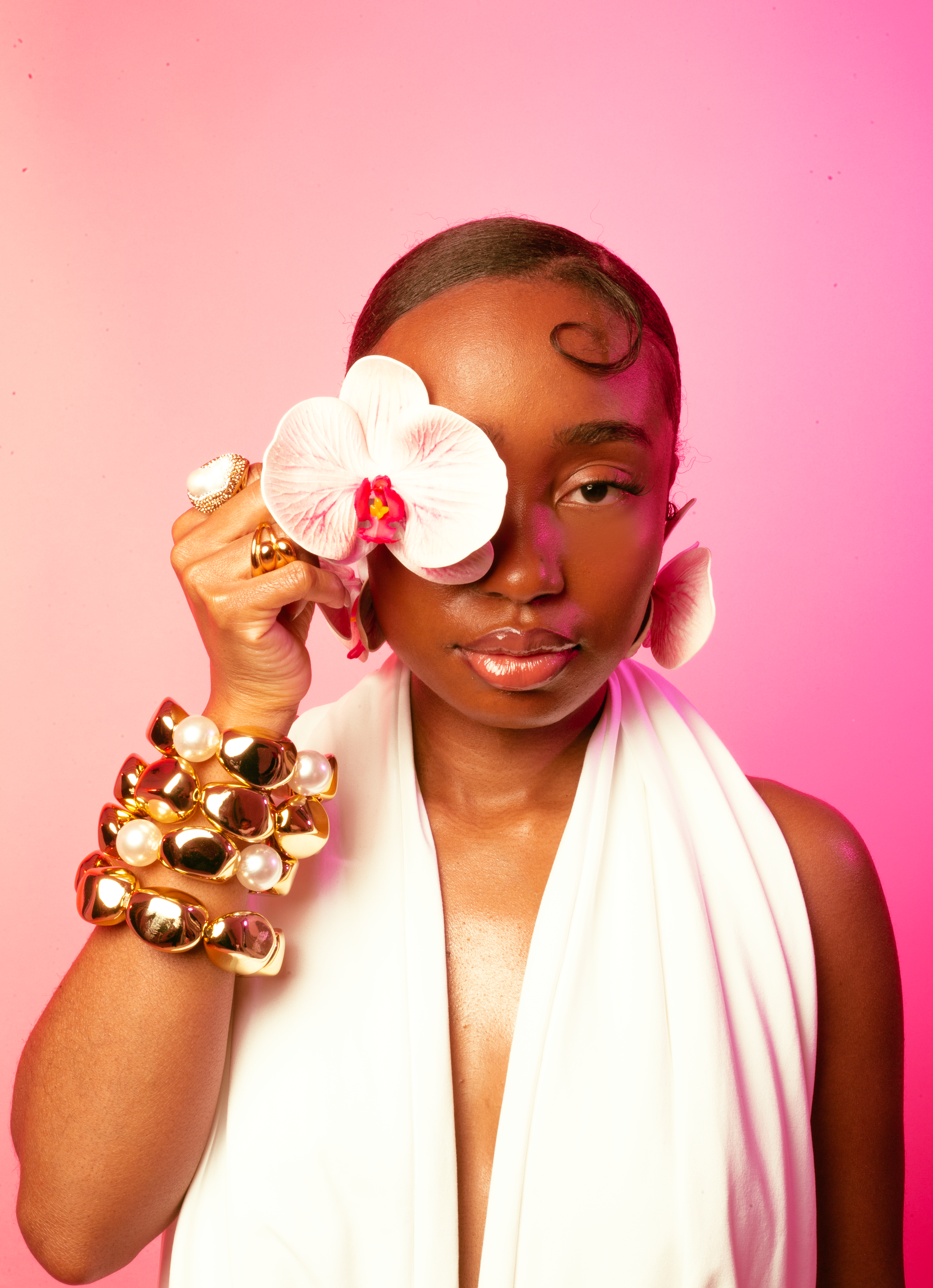 Woman holding a white orchid against a pink background